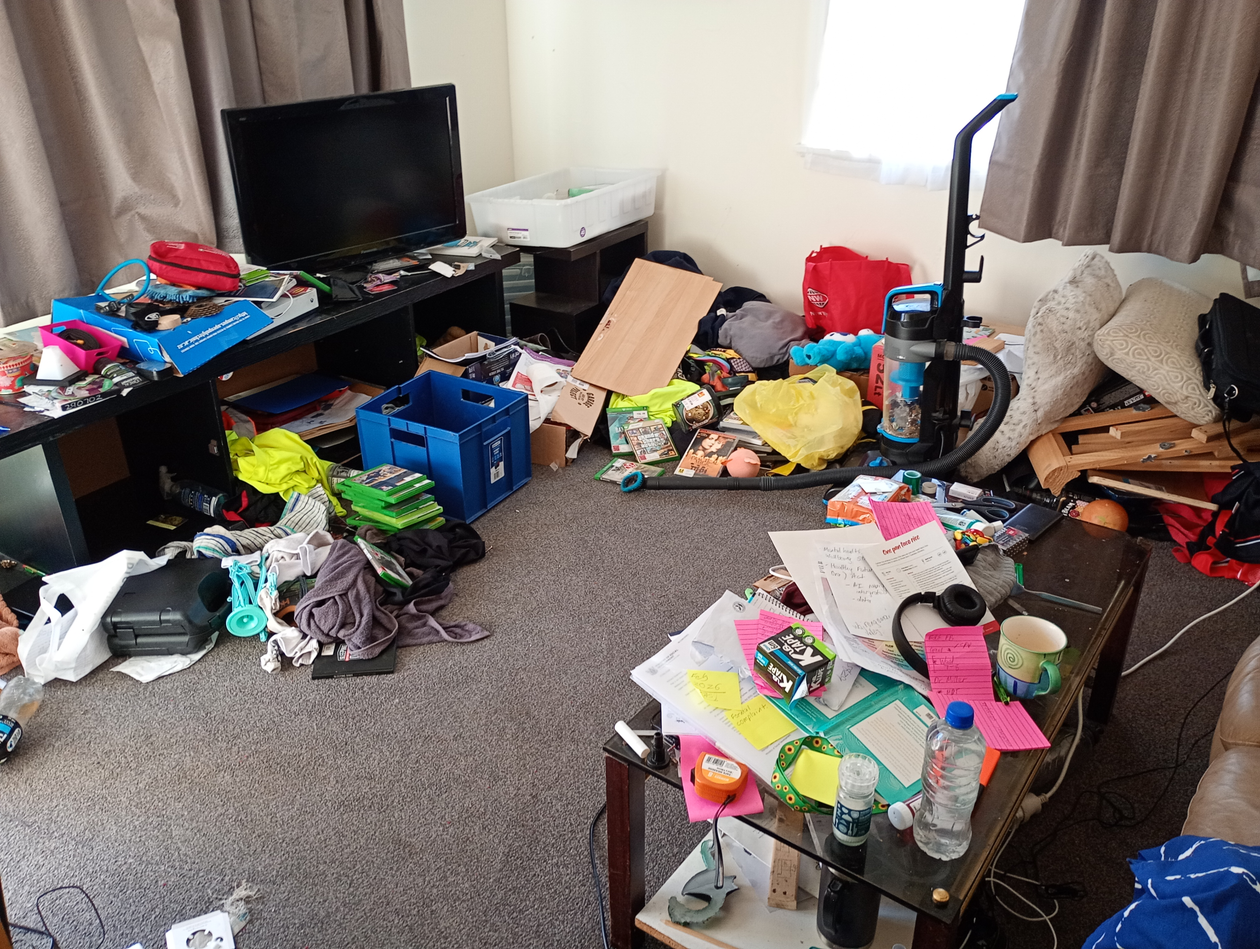 Lounge with objects cluttering the coffee table and floor
